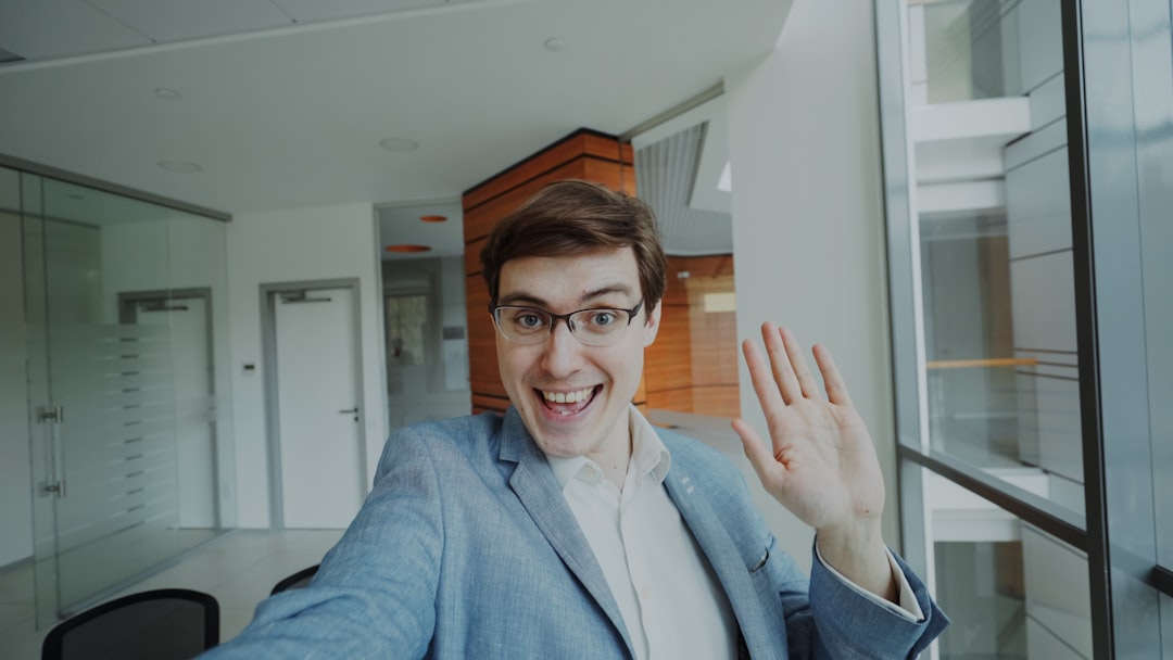Young man in glasses waves hello enthusiastically.