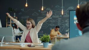 Woman celebrating success at her office desk.