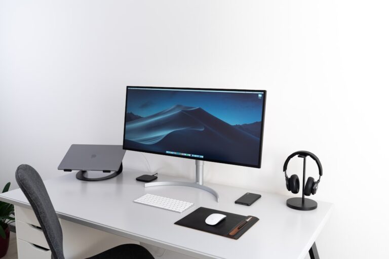 black flat widescreen computer monitor with with Apple Magic Keyboard and mouse on desk