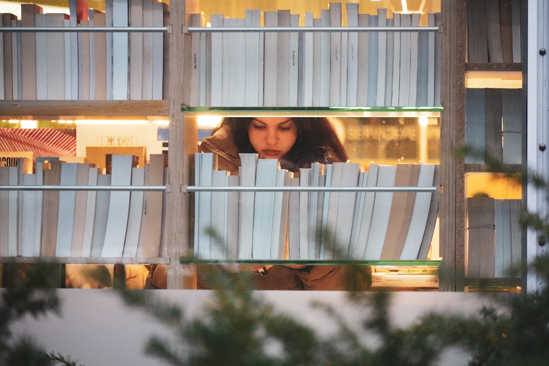 Woman peeking through bookshelves at bookshelf