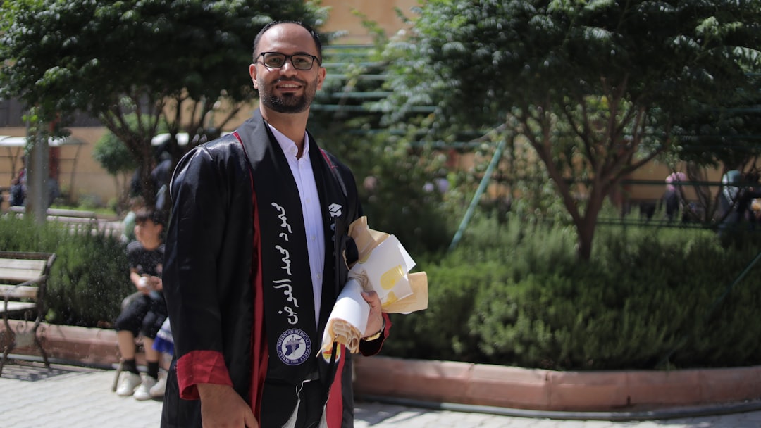 A man in a graduation gown smiles for the camera.