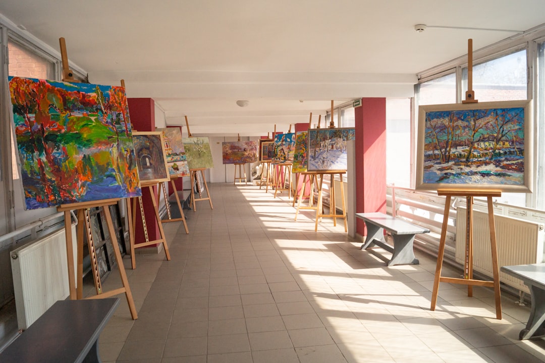 Art exhibition in a well-lit hallway with paintings on easels.