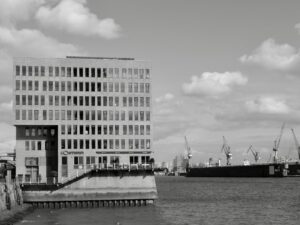 Modern building by the water with cranes in background