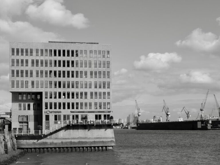 Modern building by the water with cranes in background