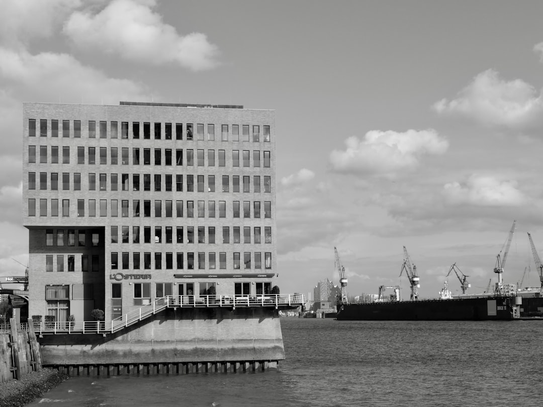Modern building by the water with cranes in background