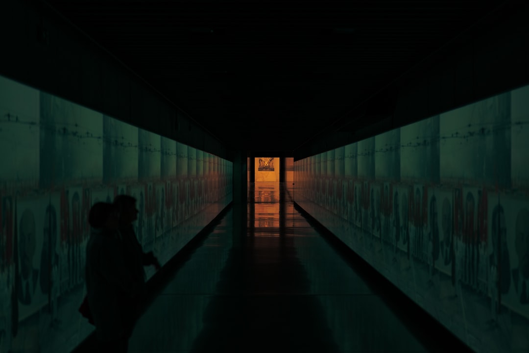 Two people walk down a dimly lit hallway.