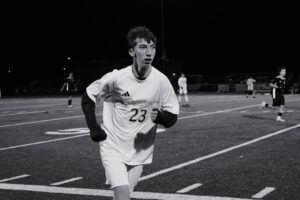 Young male soccer player running on field at night.
