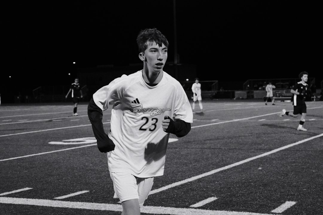 Young male soccer player running on field at night.