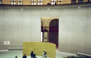 People gathered in a modern museum with concrete walls.