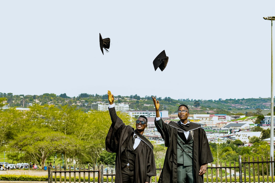 Two graduates in caps and gowns toss hats in air