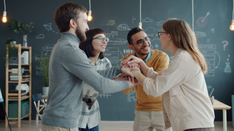 Diverse team celebrates success with a huddle.
