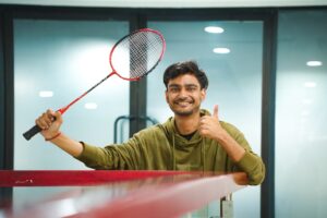 Man holding a badminton racket and giving a thumbs up