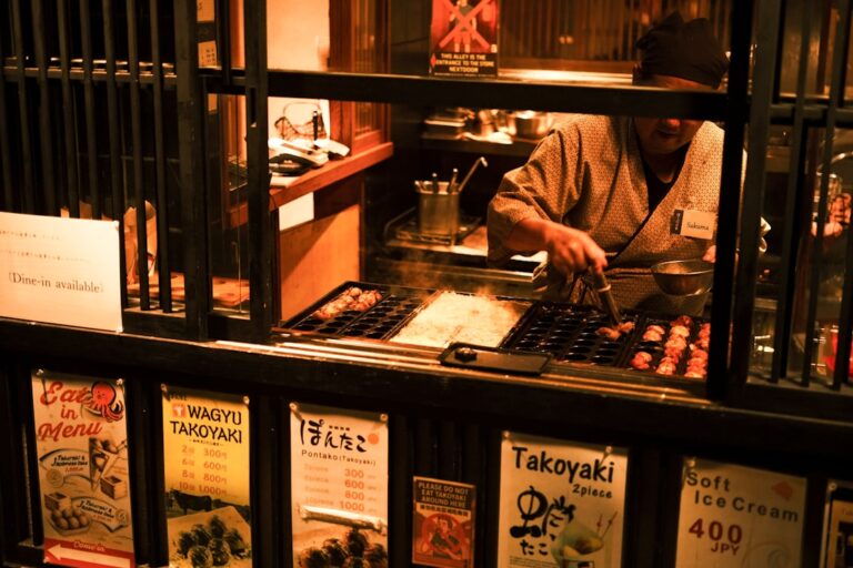 Chef preparing takoyaki at a street food stall.