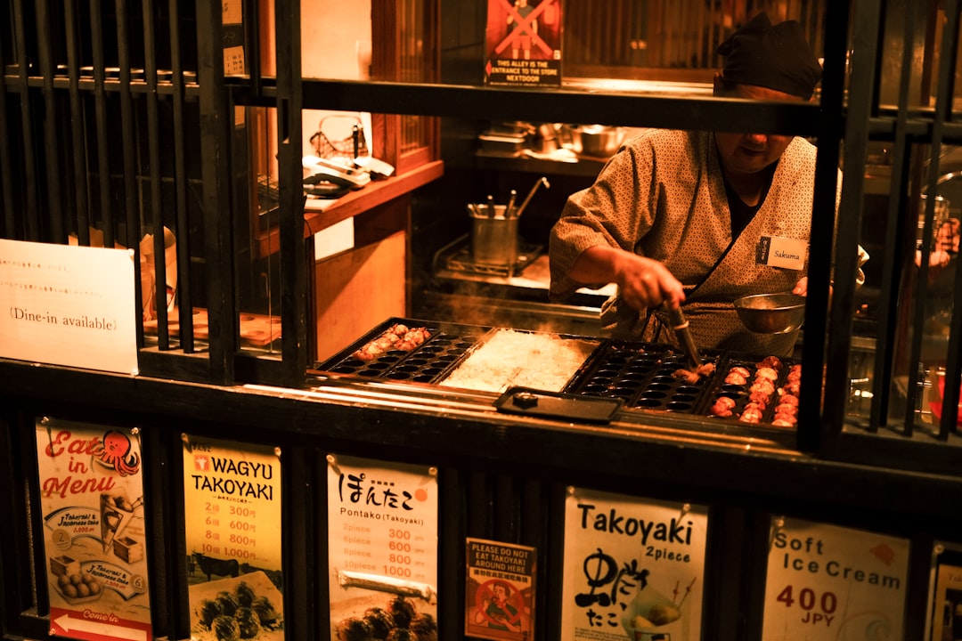 Chef preparing takoyaki at a street food stall.