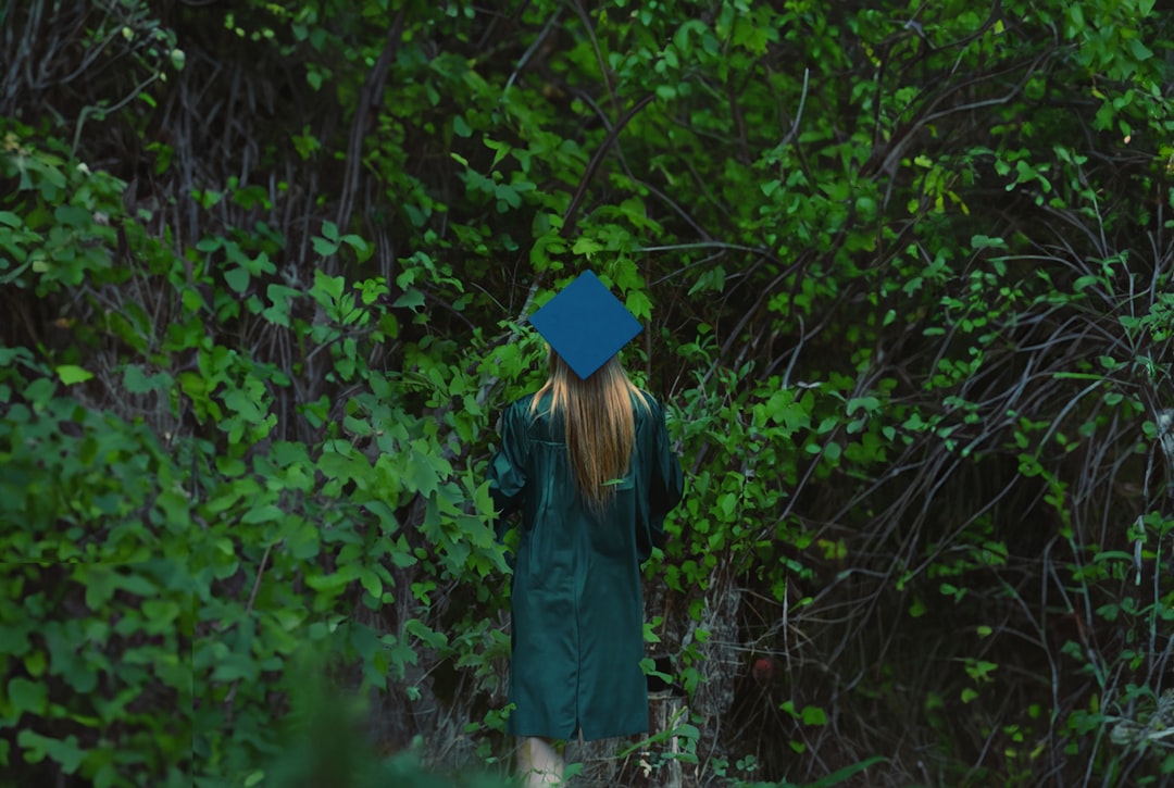 a woman in a graduation gown walks through the woods