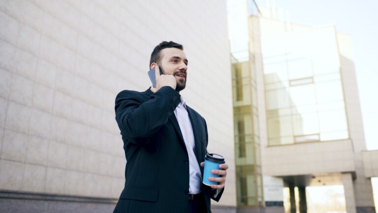 Man in suit talking on phone with coffee cup