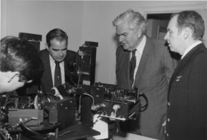 Men gathered around complex machinery in a laboratory.