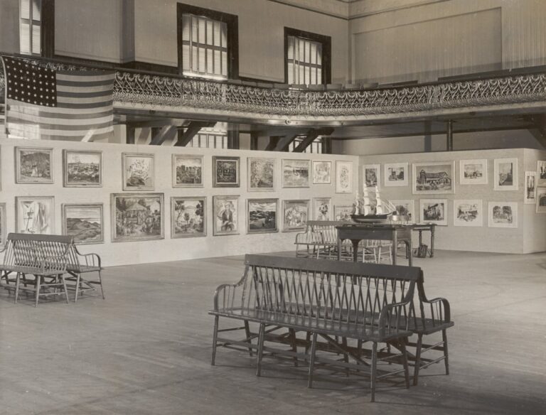 An art exhibition displays paintings within a large hall.