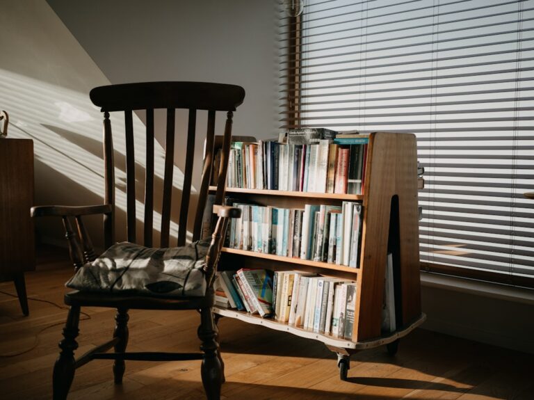 Wooden chair and bookshelf filled with books.