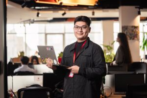 Man holding a laptop in a modern office setting.