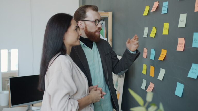Two colleagues discussing ideas on a sticky note board.