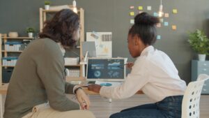 Two people looking at data on a laptop screen
