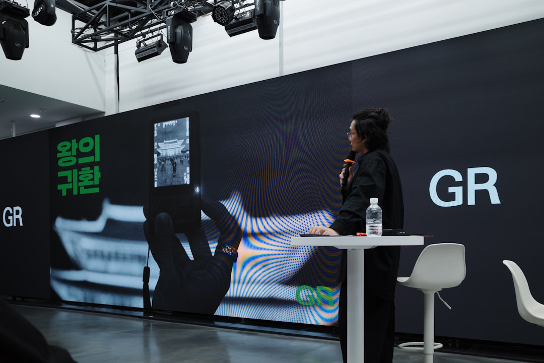 A person speaks at a presentation with a large screen.