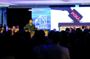 Man speaking on stage with audience watching