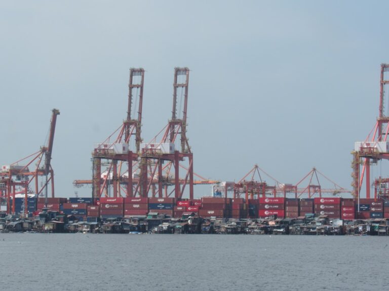 Large cranes and shipping containers at a busy port.