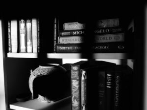 Books and a vase sit on a bookshelf.