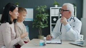 Doctor talking to mother and child at desk.