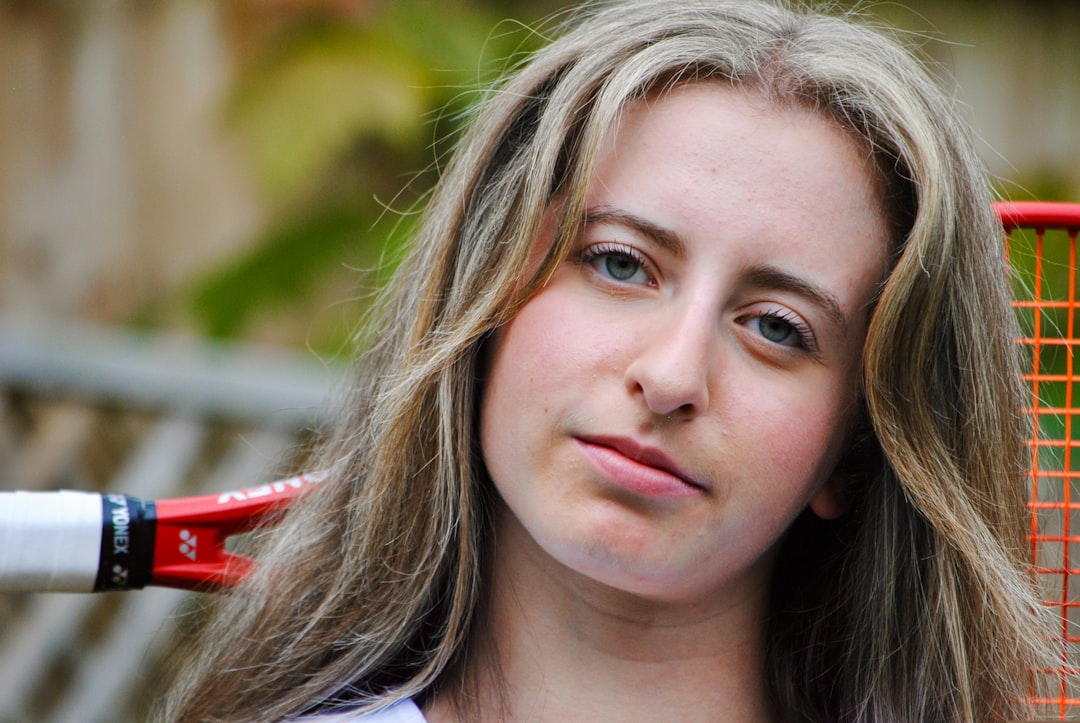 Young woman with long blonde hair and tennis racket.