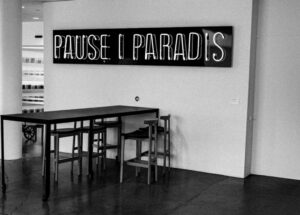 Neon sign reads pause 0 paradis above table
