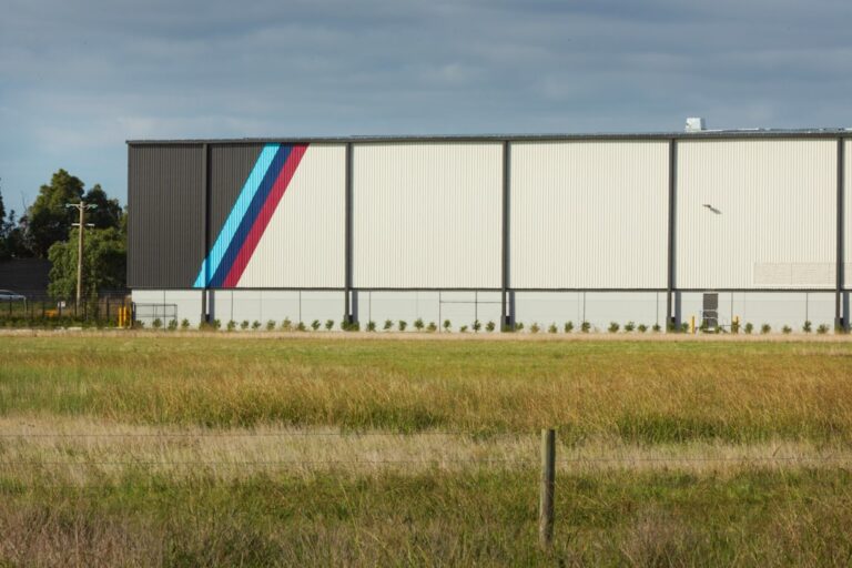 Modern building with blue, purple, red stripes and a field.