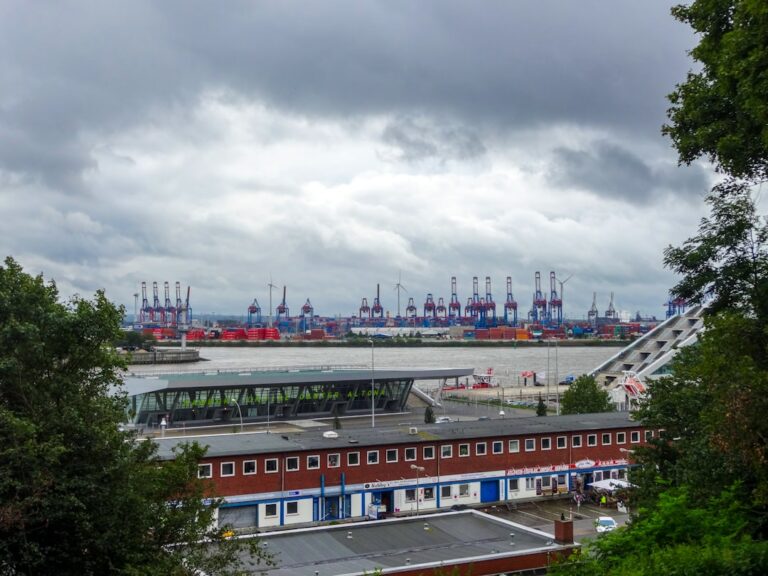 Container cranes at a busy industrial port under cloudy skies