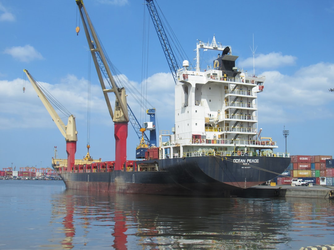 Large cargo ship docked at a busy port with cranes.