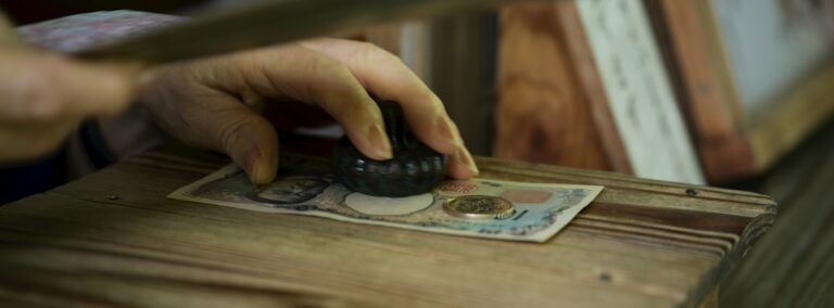 Person's hand stamping a banknote on wood.