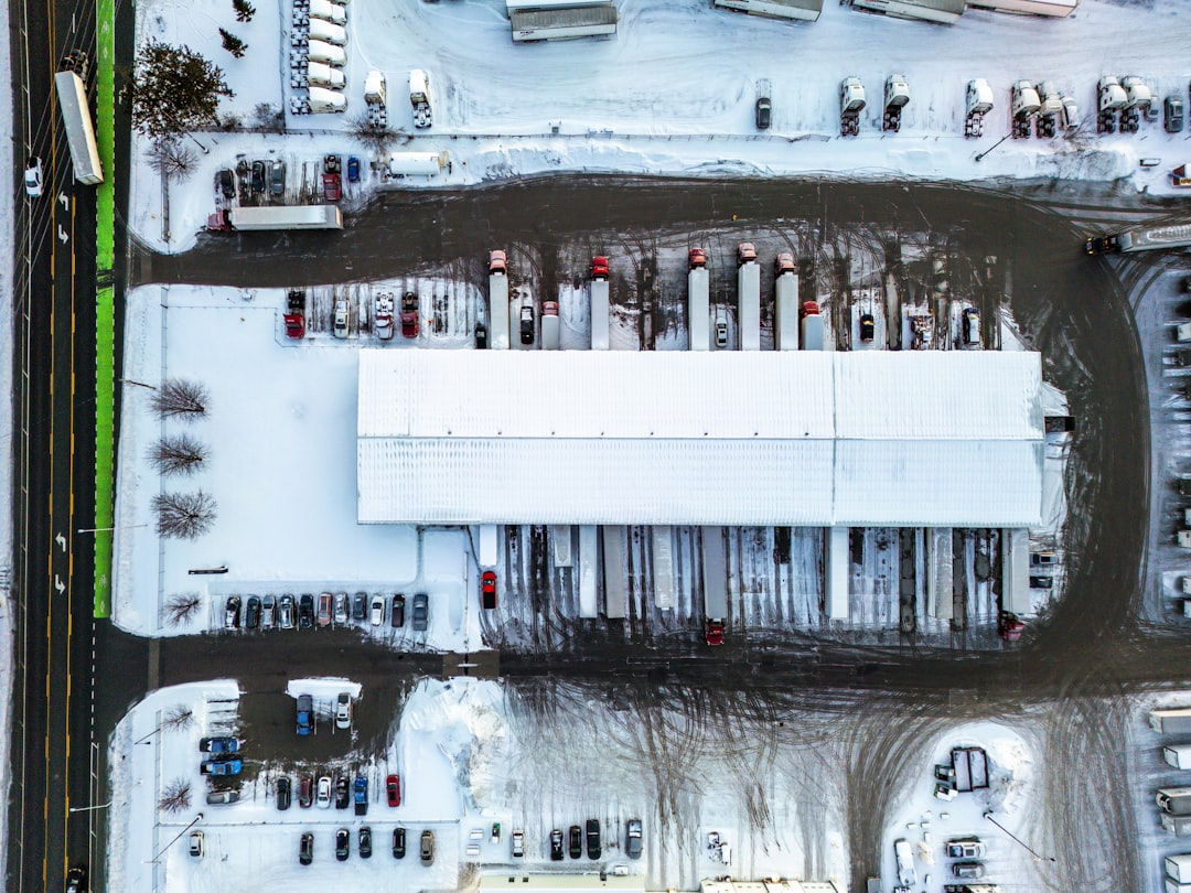 Aerial view of a snowy industrial warehouse with trucks.