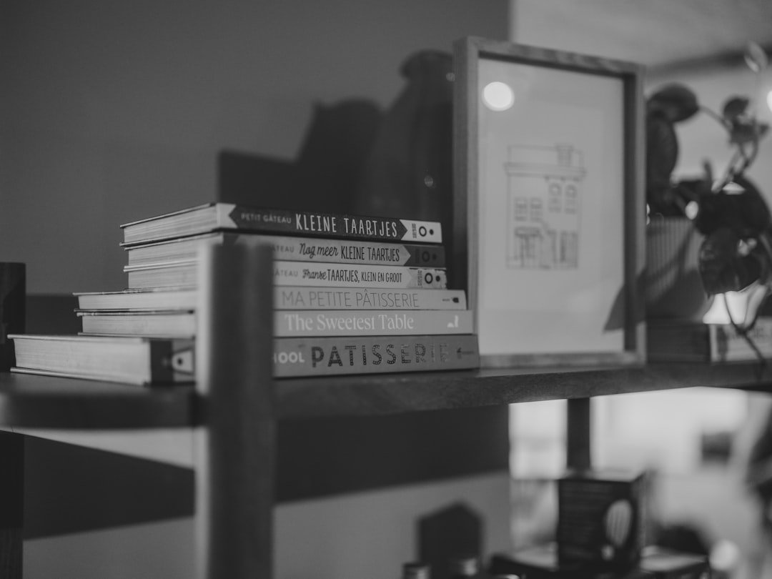 Stack of books on a shelf with framed art.
