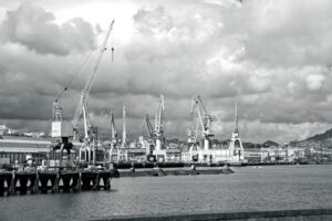 Industrial port with cranes under cloudy sky