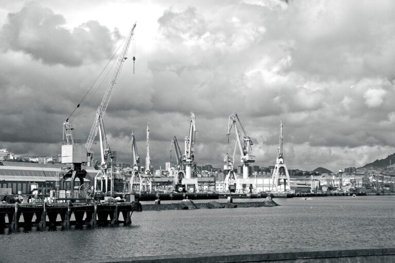 Industrial port with cranes under cloudy sky