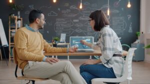 Two people collaborating at a desk with a laptop.