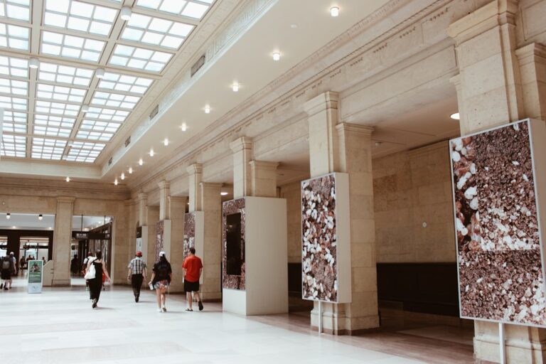 People walking through a grand hall with pillars and art.