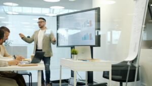 Man presenting data on a large screen to colleagues.