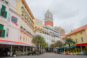 Colorful buildings and palm trees line a european-style street.