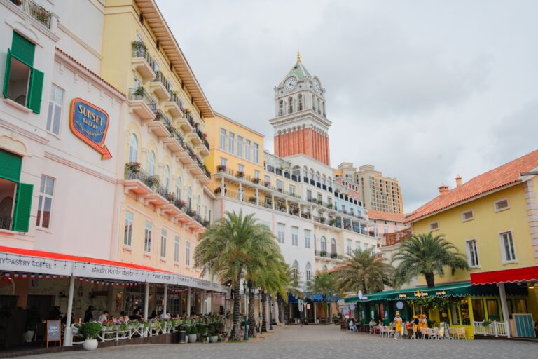 Colorful buildings and palm trees line a european-style street.