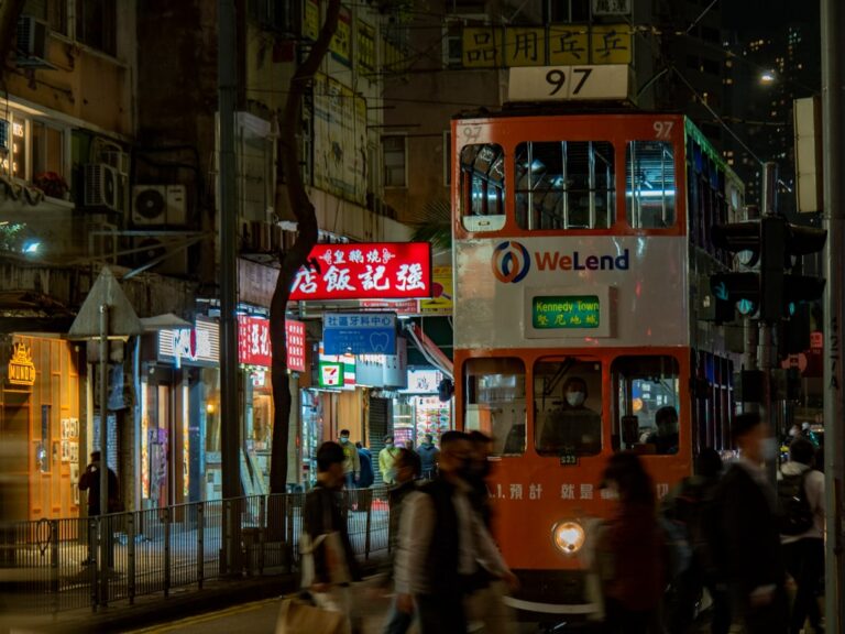 a double decker bus driving down a street at night