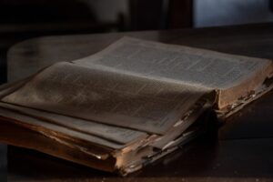 An old, weathered book lies open on a wooden table.