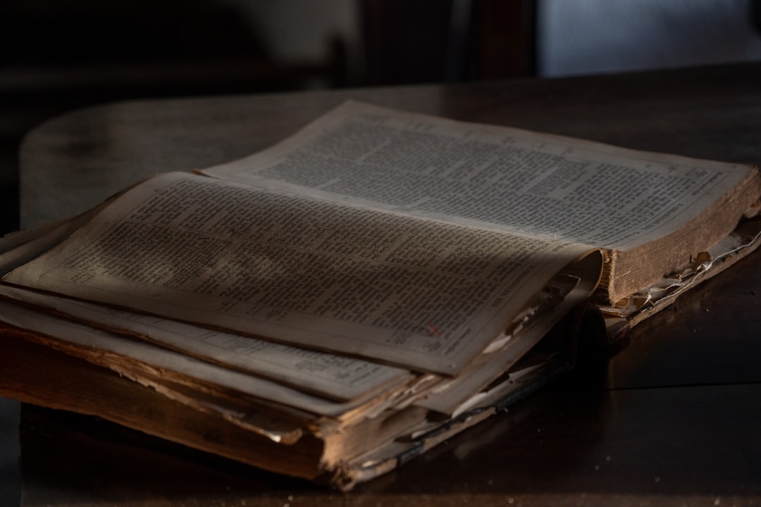 An old, weathered book lies open on a wooden table.