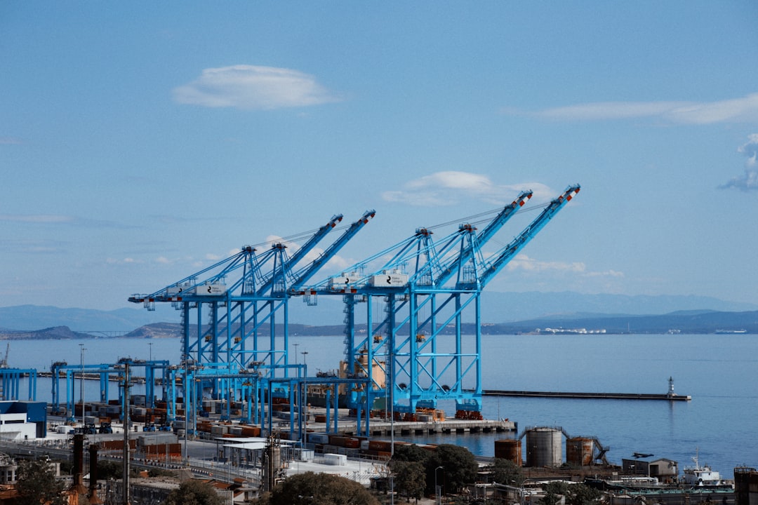 Blue container cranes dominate a port with calm water.